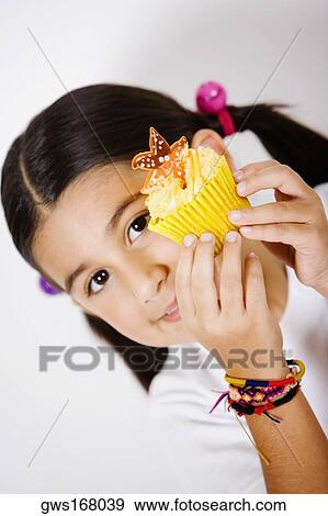 Portrait of a girl showing a cupcake View Large Photo Image Stock Photo - Portrait of a girl showing a cupcake. Fotosearch