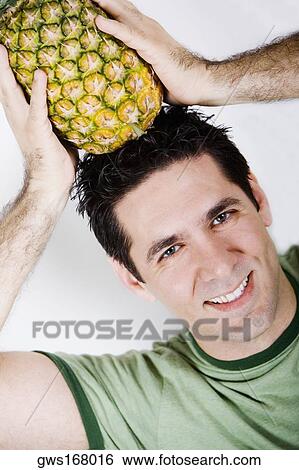 Portrait of a mid adult man holding a pineapple on his head and smiling View Large Photo Image Stock Photograph - Portrait of a mid adult man holding a pineapple on his head and smiling. Fotosearch