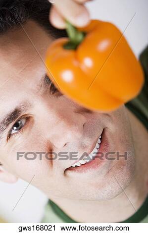 Portrait of a mid adult man holding an orange bell pepper and smiling View Large Photo Image Stock Image - Portrait of a mid adult man holding an orange bell pepper and smiling. Fotosearch
