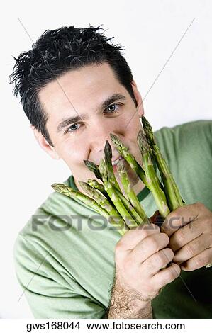 Portrait of a mid adult man holding asparagus and smiling View Large Photo Image Picture - Portrait of a mid adult man holding asparagus and smiling. Fotosearch