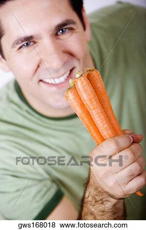 Portrait of a mid adult man holding carrots and smiling View Large Photo Image Stock Photo - Portrait of a mid adult man holding carrots and smiling. Fotosearch