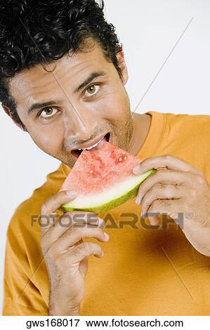 Portrait of a young man eating a slice of a watermelon View Large Photo Image Stock Photo - Portrait of a young man eating a slice of a watermelon. Fotosearch