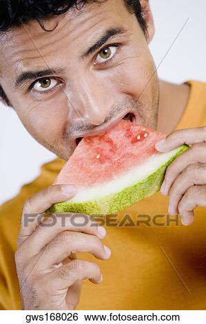 Portrait of a young man eating a slice of a watermelon View Large Photo Image Stock Photograph - Portrait of a young man eating a slice of a watermelon. Fotosearch