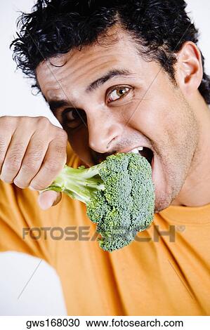 Portrait of a young man eating a broccoli View Large Photo Image Stock Image - Portrait of a young man eating a broccoli. Fotosearch