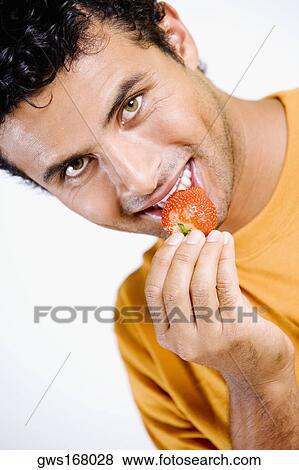 Portrait of a young man eating a strawberry View Large Photo Image Stock Photo - Portrait of a young man eating a strawberry. Fotosearch