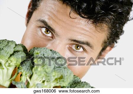 Portrait of a young man holding broccoli in front of his face View Large Photo Image Stock Photograph - Portrait of a young man holding broccoli in front of his face. Fotosearch