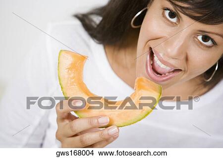 Portrait of a young woman eating a slice of melon View Large Photo Image Picture - Portrait of a young woman eating a slice of melon. Fotosearch