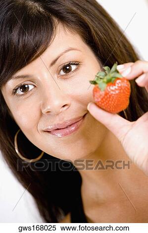 Portrait of a young woman holding a strawberry and smiling View Large Photo Image Stock Photography - Portrait of a young woman holding a strawberry and smiling. Fotosearch