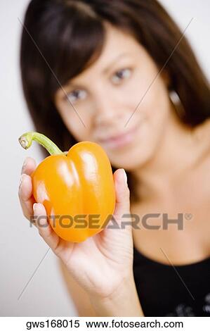 Portrait of a young woman holding an orange bell pepper View Large Photo Image Stock Photography - Portrait of a young woman holding an orange bell pepper. Fotosearch