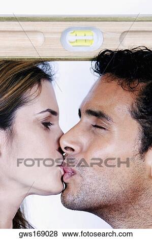 Close-up of a young couple kissing each other with a spirit level on their heads View Large Photo Image Stock Photo - Close-up of a young couple kissing each other with a spirit level on their heads. Fotosearch