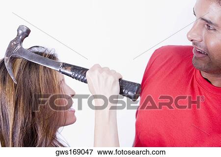 Close-up of a young woman swinging a hammer at a young man View Large Photo Image Stock Photo - Close-up of a young woman swinging a hammer at a young man. Fotosearch