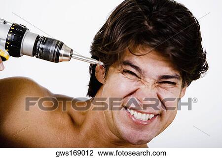 Mid adult man holding a drill machine against his head View Large Photo Image Stock Image - Mid adult man holding a drill machine against his head. Fotosearch