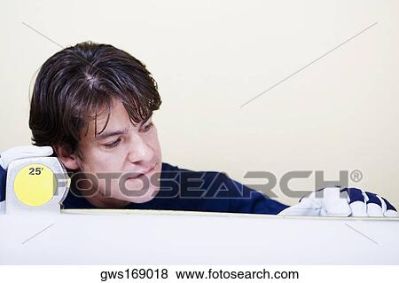 Mid adult man measuring with a measuring tape View Large Photo Image Stock Photo - Mid adult man measuring with a measuring tape. Fotosearch