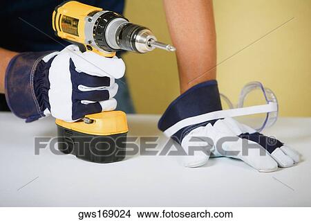 Picture - Mid section view of a man holding a drill machine. Fotosearch