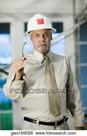 Portrait of a male architect looking angry and holding a sunglasses View Large Photo Image Stock Photograph - Portrait of a male architect looking angry and holding a sunglasses. Fotosearch