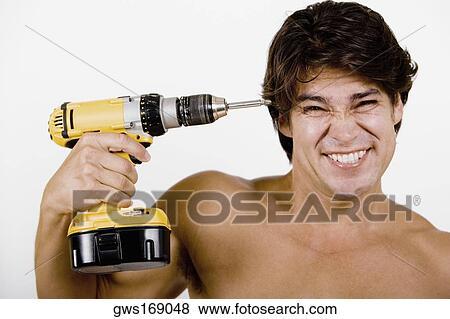 Portrait of a mid adult man holding a drill machine against his head View Large Photo Image Stock Photo - Portrait of a mid adult man holding a drill machine against his head. Fotosearch