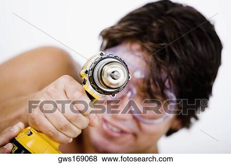Stock Photo - Portrait of a mid adult man holding a drill machine. Fotosearch