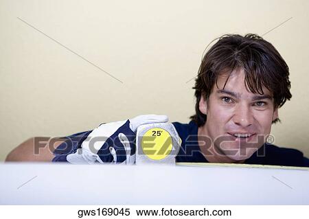 Portrait of a mid adult man measuring with a measuring tape and smiling View Large Photo Image Stock Photography - Portrait of a mid adult man measuring with a measuring tape and smiling. Fotosearch