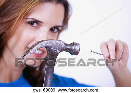Portrait of a mid adult woman holding a nail and a claw hammer View Large Photo Image Stock Photo - Portrait of a mid adult woman holding a nail and a claw hammer. Fotosearch
