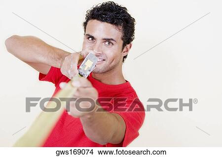Portrait of a young man holding a measuring tape and smiling View Large Photo Image Picture - Portrait of a young man holding a measuring tape and smiling. Fotosearch