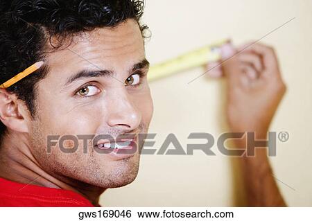 Portrait of a young man measuring with a measuring tape View Large Photo Image Stock Photograph - Portrait of a young man measuring with a measuring tape. Fotosearch