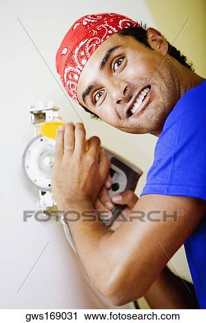 Stock Image - Portrait of a young man working with a circular saw. Fotosearch