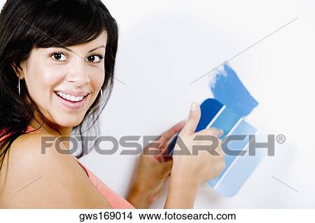 Picture - Portrait of a young woman holding a color swatch against a wall. Fotosearch