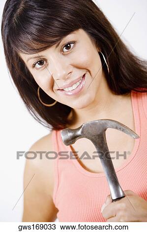 Portrait of a young woman holding a hammer and smiling View Large Photo Image Stock Image - Portrait of a young woman holding a hammer and smiling. Fotosearch