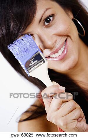 Portrait of a young woman holding a paintbrush and smiling View Large Photo Image Stock Photography - Portrait of a young woman holding a paintbrush and smiling. Fotosearch