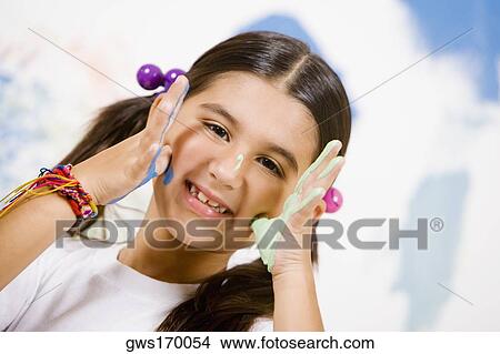 Portrait of a girl with paint on her palms and touching her cheeks View Large Photo Image Picture - Portrait of a girl with paint on her palms and touching her cheeks. Fotosearch