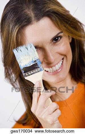 Portrait of a mid adult woman holding a paintbrush and smiling View Large Photo Image Picture - Portrait of a mid adult woman holding a paintbrush and smiling. Fotosearch