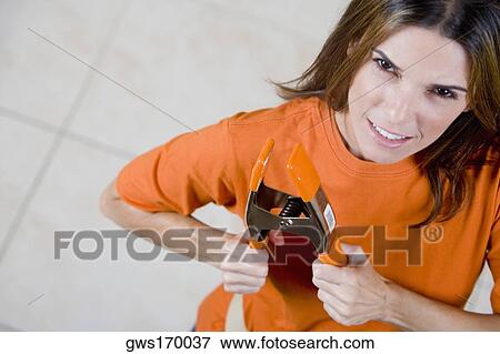 Stock Photo - Portrait of a mid adult woman holding a clamp and smiling. Fotosearch