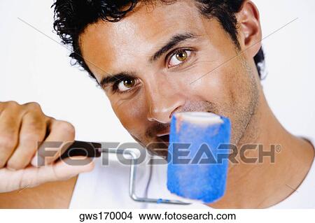 Portrait of a young man holding a paint roller View Large Photo Image Picture - Portrait of a young man holding a paint roller. Fotosearch
