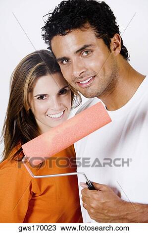 Portrait of a young man holding a paint roller standing with a mid adult woman View Large Photo Image Stock Image - Portrait of a young man holding a paint roller standing with a mid adult woman. Fotosearch