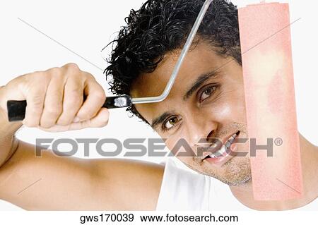 Portrait of a young man holding a paint roller and smiling View Large Photo Image Stock Photo - Portrait of a young man holding a paint roller and smiling. Fotosearch