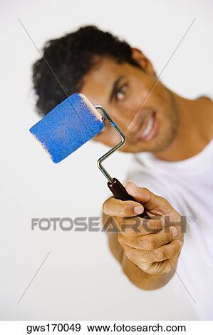 Stock Photo - Portrait of a young man holding a paint roller and smiling. Fotosearch