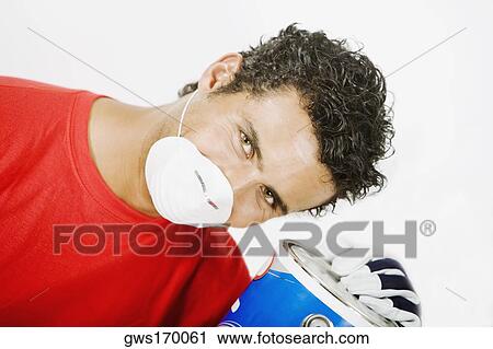 Stock Image - Portrait of a young man wearing a pollution mask and holding a paint can. Fotosearch