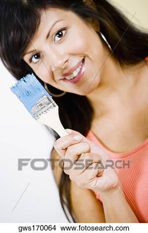 Portrait of a young woman holding a paintbrush and smiling View Large Photo Image Picture - Portrait of a young woman holding a paintbrush and smiling. Fotosearch