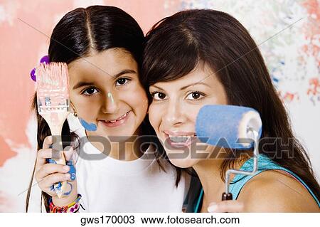 Portrait of a young woman holding a paint roller with her daughter holding a paintbrush View Large Photo Image Stock Image - Portrait of a young woman holding a paint roller with her daughter holding a paintbrush. Fotosearch