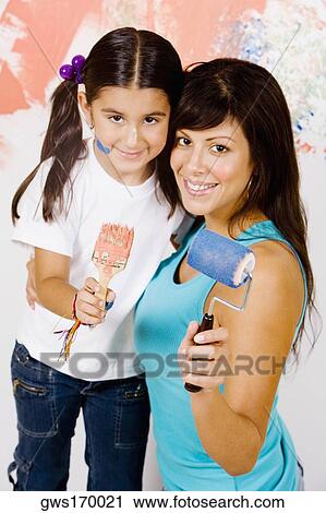 Portrait of a young woman holding a paint roller with her daughter holding a paintbrush View Large Photo Image Stock Image - Portrait of a young woman holding a paint roller with her daughter holding a paintbrush. Fotosearch
