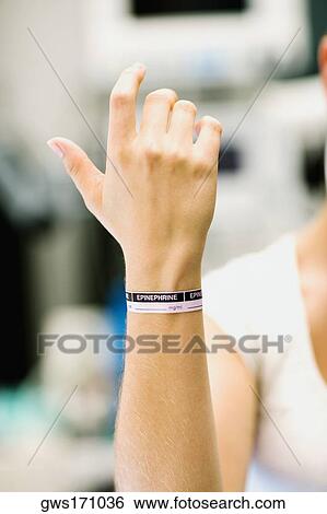 Stock Photograph - Close-up of a woman's hand with dosage tag around her wrist. Fotosearch