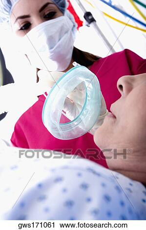 Low angle view of a female surgeon putting an oxygen mask on a patient View Large Photo Image Stock Image - Low angle view of a female surgeon putting an oxygen mask on a patient. Fotosearch