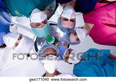 Stock Image - Low angle view of surgeons in an operating room. Fotosearch