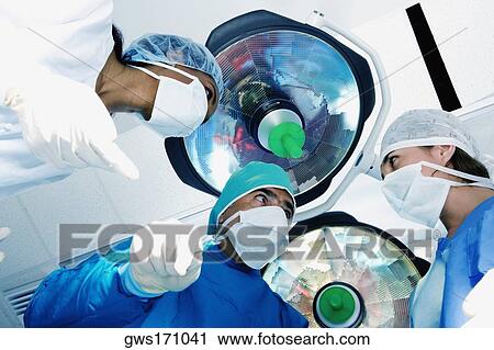 Stock Image - Male surgeon and two female surgeons in an operating room. Fotosearch