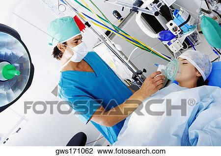 Male surgeon putting an oxygen mask on the mouth of a female patient View Large Photo Image Stock Image - Male surgeon putting an oxygen mask on the mouth of a female patient. Fotosearch