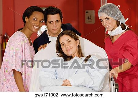 Two female doctors and a male doctor pushing a female patient on a hospital gurney View Large Photo Image Stock Image - Two female doctors and a male doctor pushing a female patient on a hospital gurney. Fotosearch