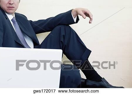 Businessman sitting in front of a laptop View Large Photo Image Stock Photo - Businessman sitting in front of a laptop. Fotosearch