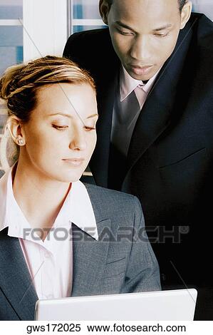 Stock Photography - Close-up of a businessman and a businesswoman looking at a laptop. Fotosearch