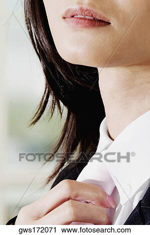 Stock Image - Close-up of a businesswoman adjusting her tie. Fotosearch