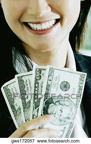Close-up of a businesswoman holding American dollar bills and smiling View Large Photo Image Stock Photo - Close-up of a businesswoman holding American dollar bills and smiling. Fotosearch